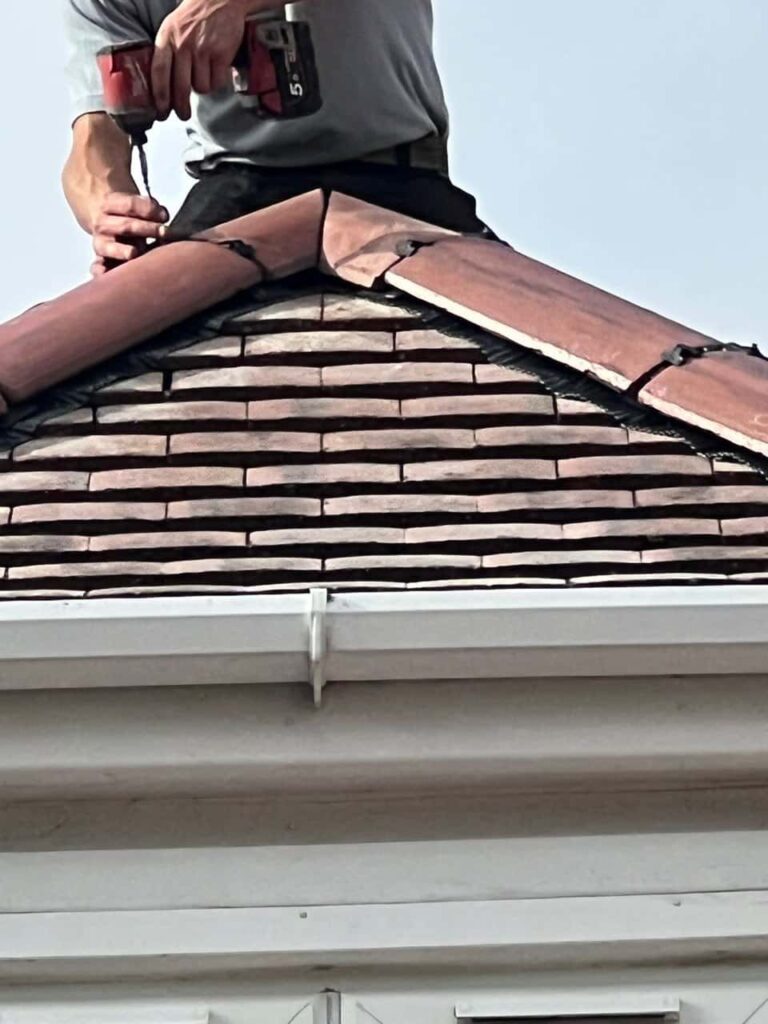 This is a photo of one of the operatives of Haverhill Roofing Repairs installing new ridge tiles