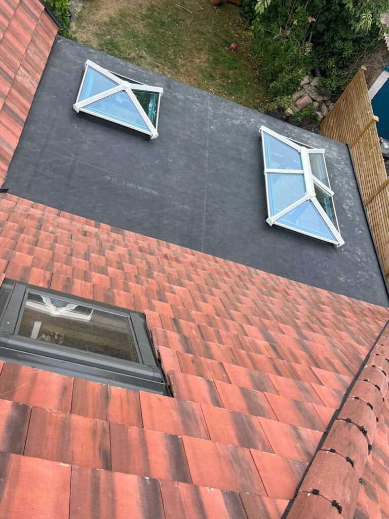 This is a photo taken from the roof ridge looking down a tiled pitched roof on to a flat roof. Works carried out by Haverhill Roofing Repairs